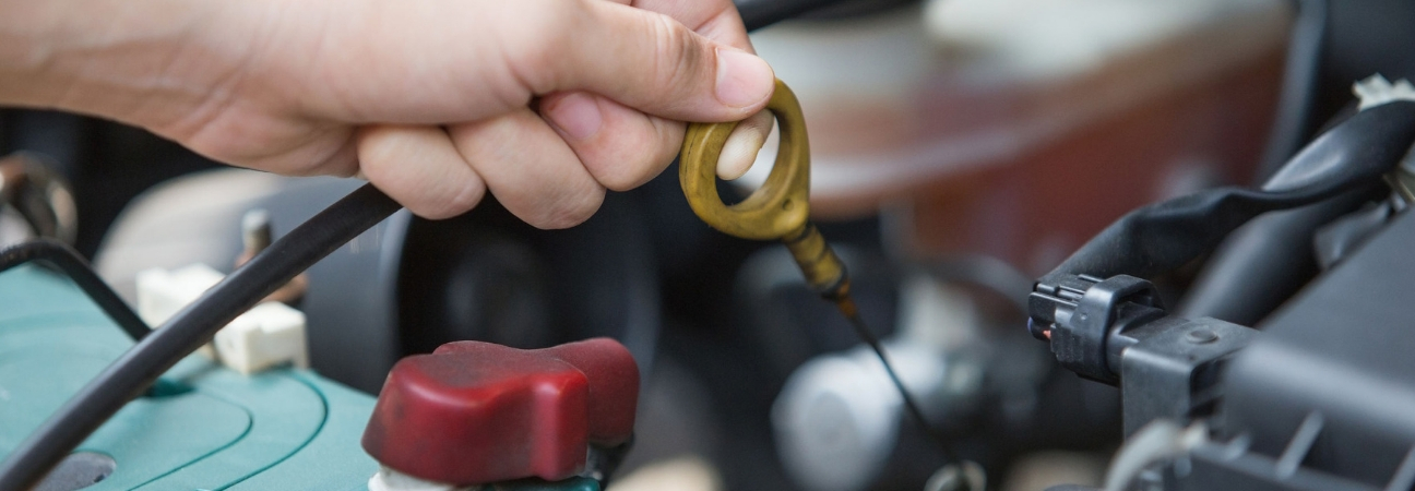 Hand pulling dipstick for oil change